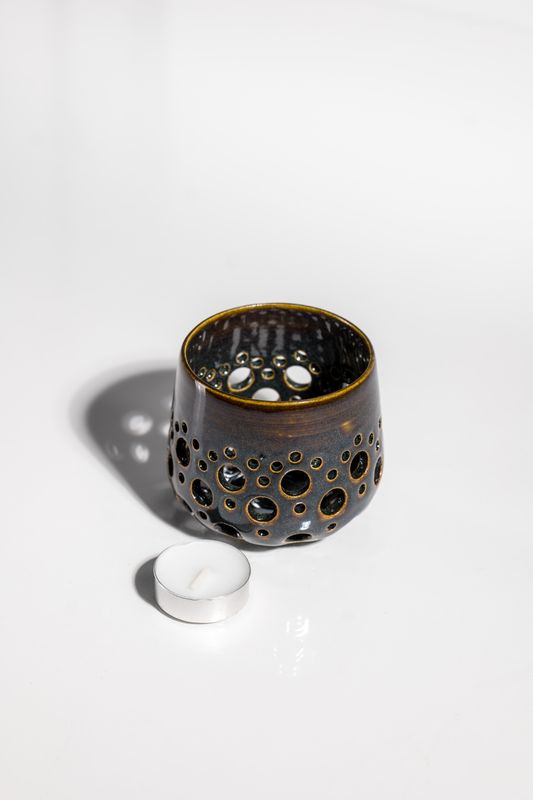Ceramic candleholder with holes punched in it to allow light to shine from the tealight candle. handmade in the USA by locals