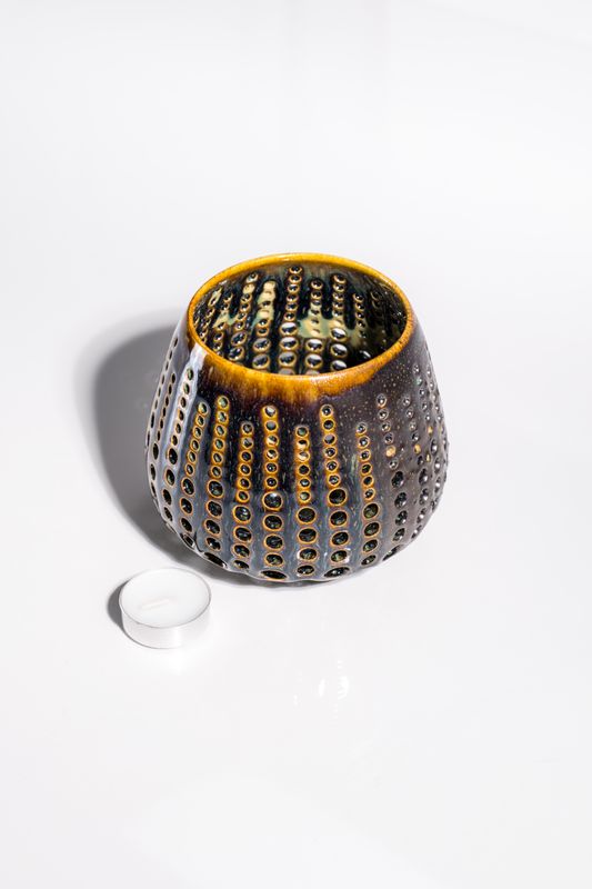 Large ceramic candleholder with various holes that allow light to shine through and cast shadows. Handmade in the USA