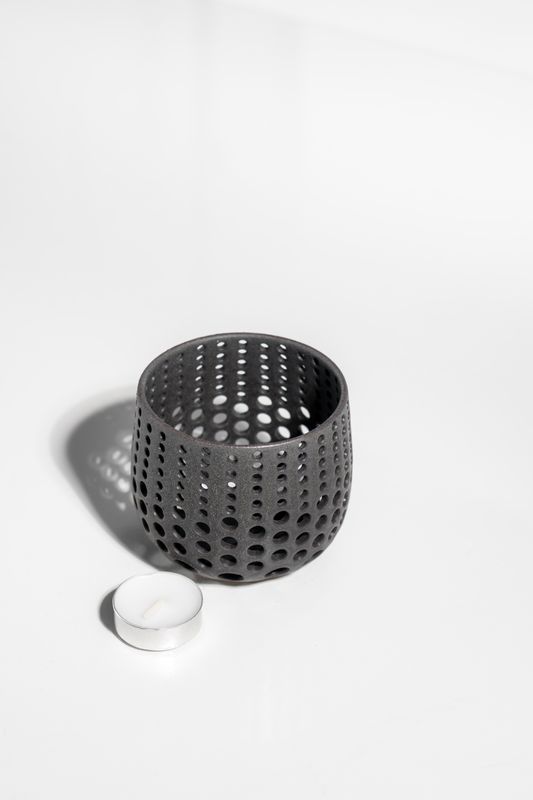 dark and moody clay candleholder made of stone ware ceramics and has holes punched in it to shine light from tealight.