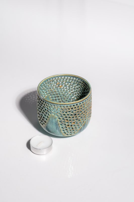 Hand carved ceramic candleholder with a wavy pattern to allow light to shine through from the votive or tealight candleholder