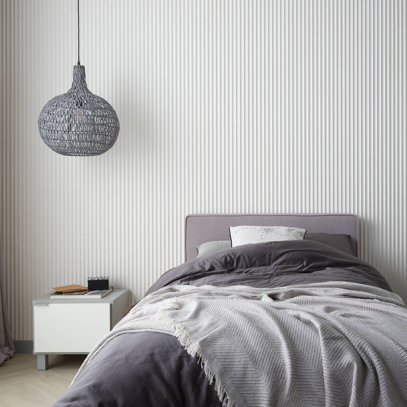 Akustikpaneel in weiß in einem Schlafzimmer mit unterschiedlichen Grautönen in der Einrichtung. Gewellte Stäbe