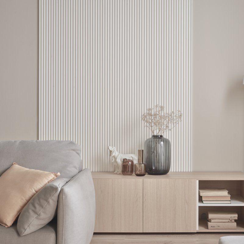 Weißes Akustikpaneel mit dünnen Stäben in einem Wohnzimmer mit beigen Möbeln