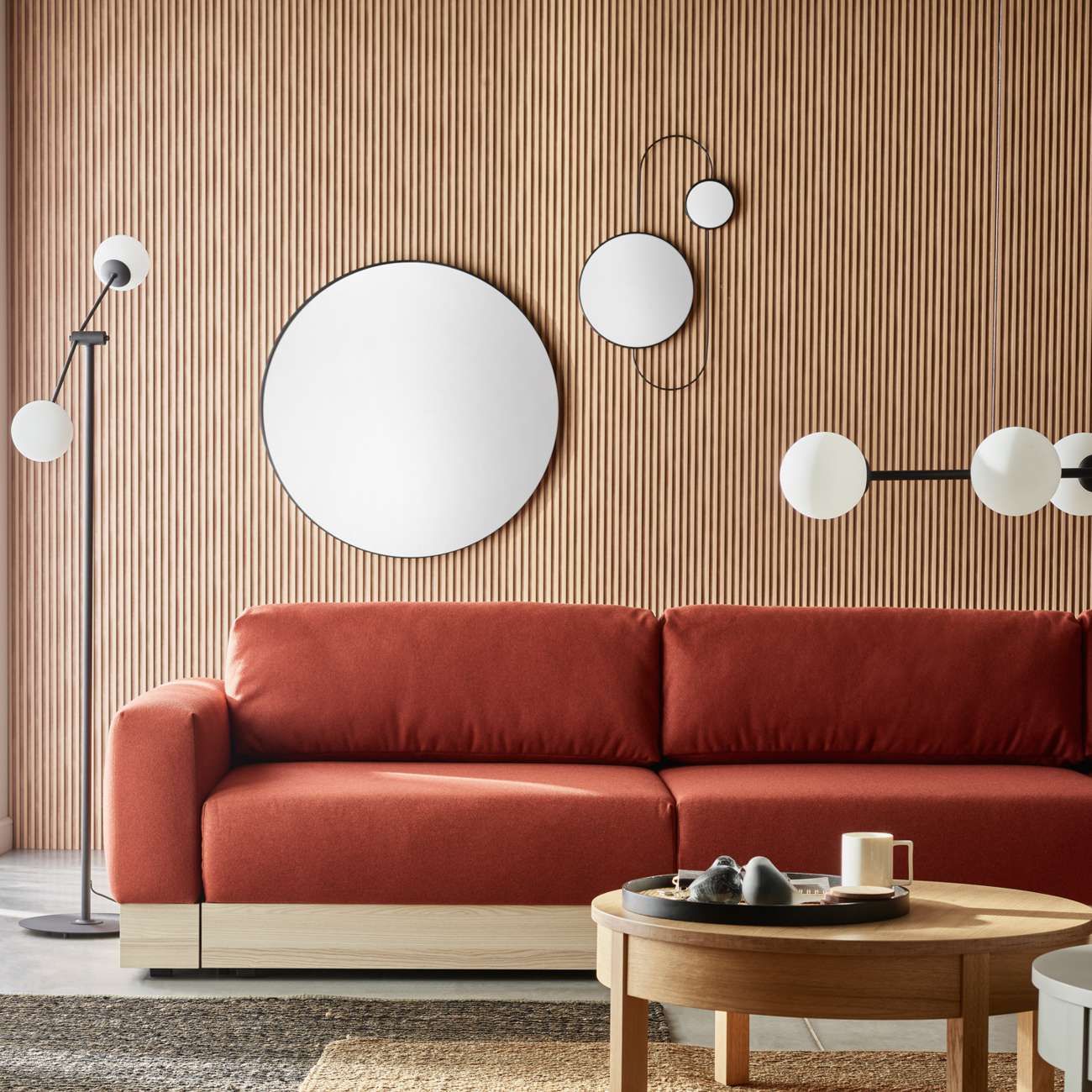 Akustikpaneel in hellbraun hinter einer roten Couch in einem Wohnzimmer mit hellbraunen Holzmöbeln