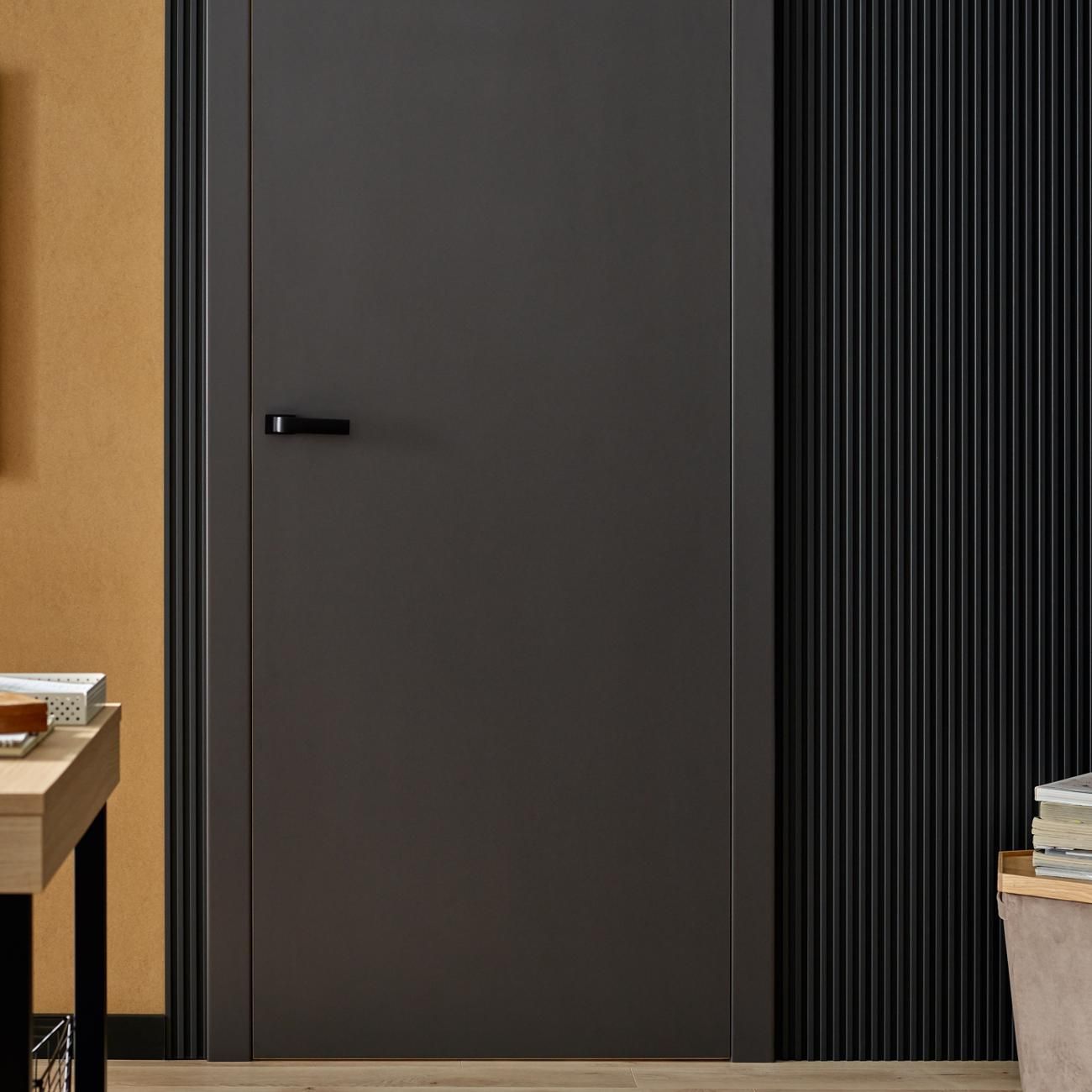 Akustikpaneel in Anthrazit neben einer dunkelgrauen Tür und einer braunen Wand.
