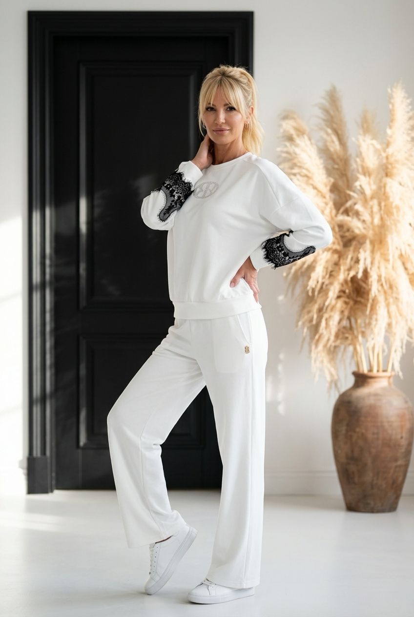 Kobieta w białym komplecie dresowym z czarną koronką na rękawach i szerokimi spodniami