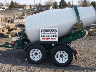 Green and white tow-behind concrete mixer trailer with a Soracco RENT ME sign, parked on yard gravel.