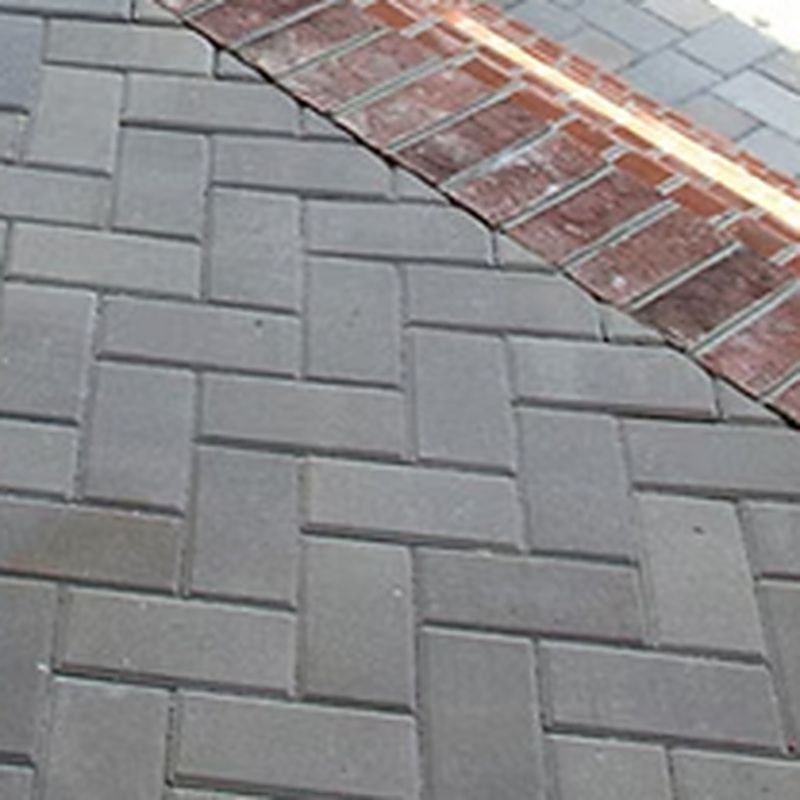 Grey herringbone paver patio with a red clay brick soldier course border running along the edge.