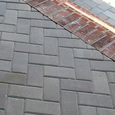 Grey herringbone paver patio with a red clay brick soldier course border running along the edge.