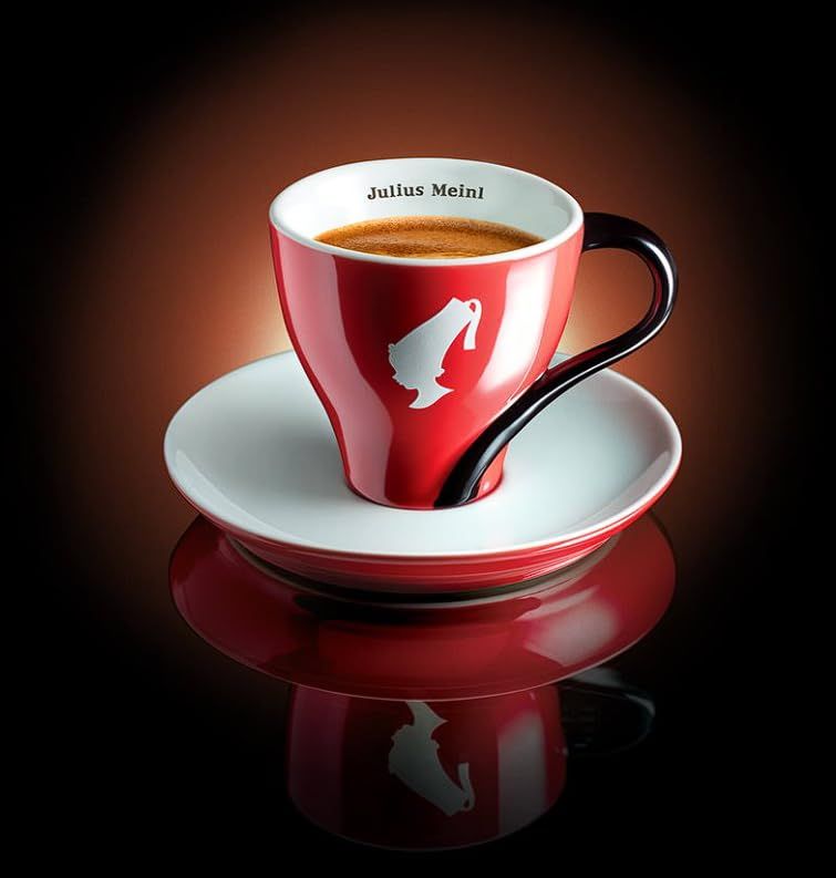Julius Meinl Espresso Arabica 1kg, red coffee cup with white saucer and black handle on dark backgr…