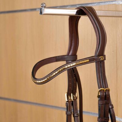 alt="Détail cuir marron et ornements clincher laiton doré frontal Dy’on"