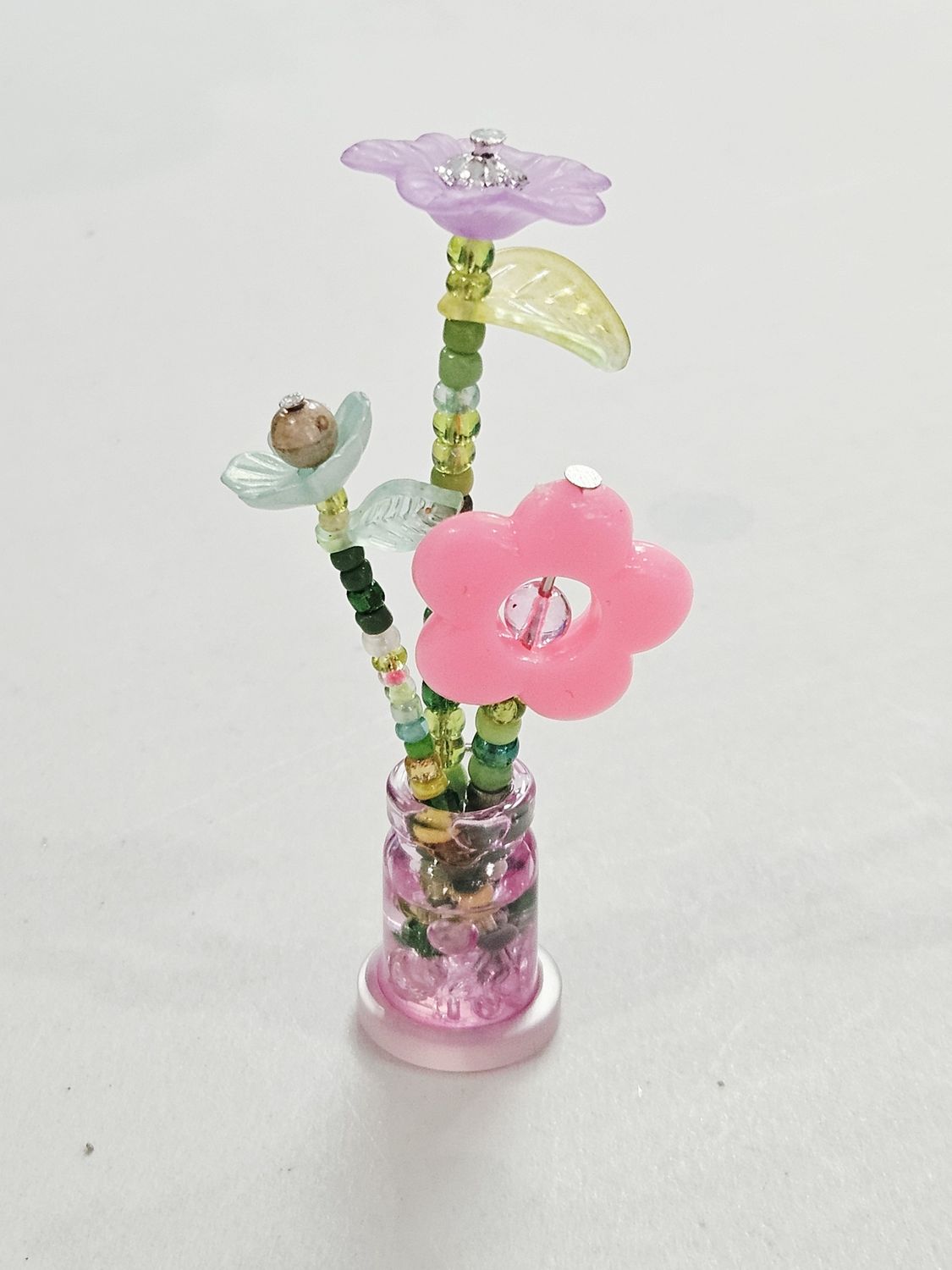 Purple, pink, and blue beaded flowers in mini pink vase