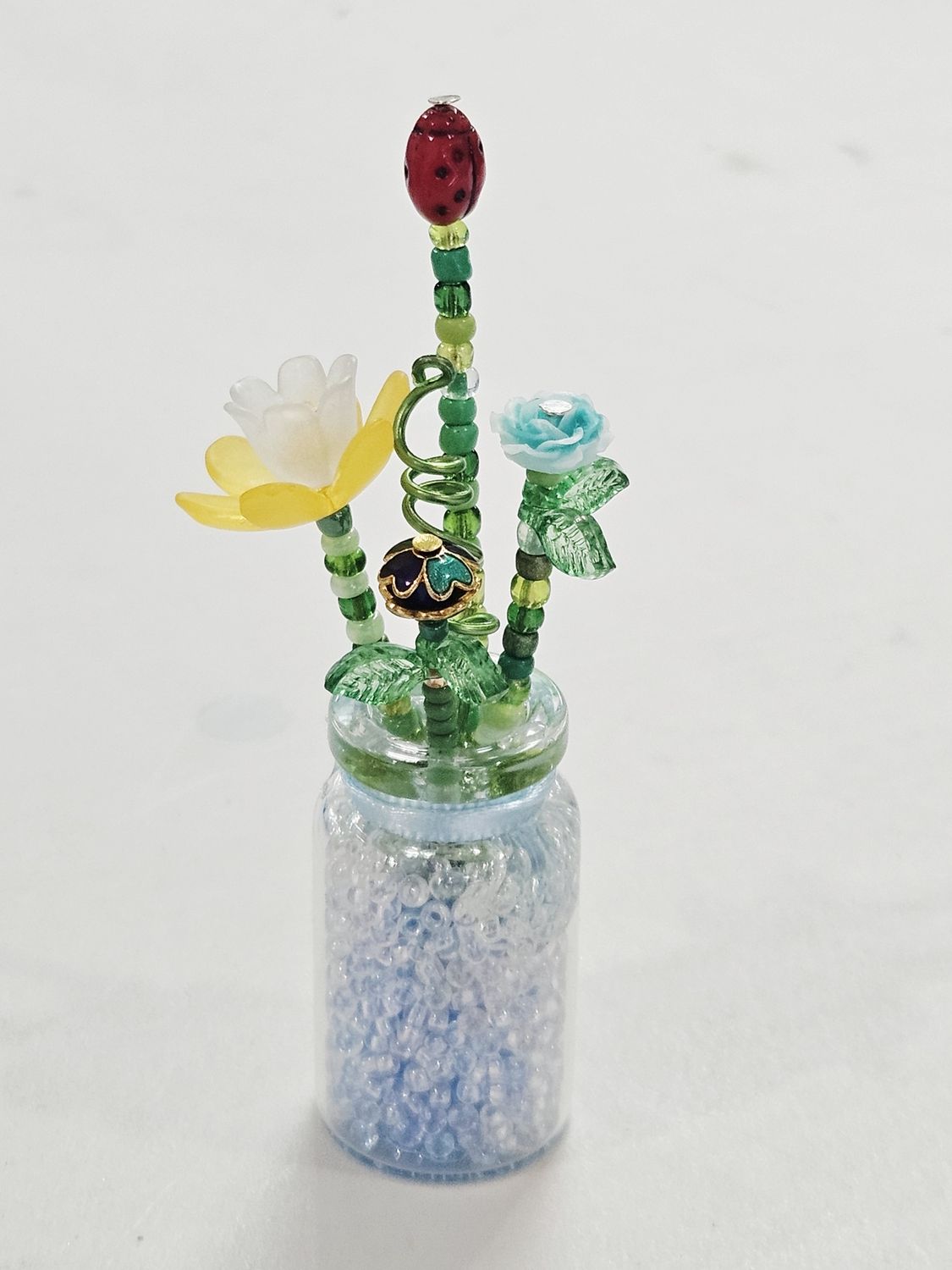 Blue and Yellow Beaded Flowers with Ladybug in Clear Vase