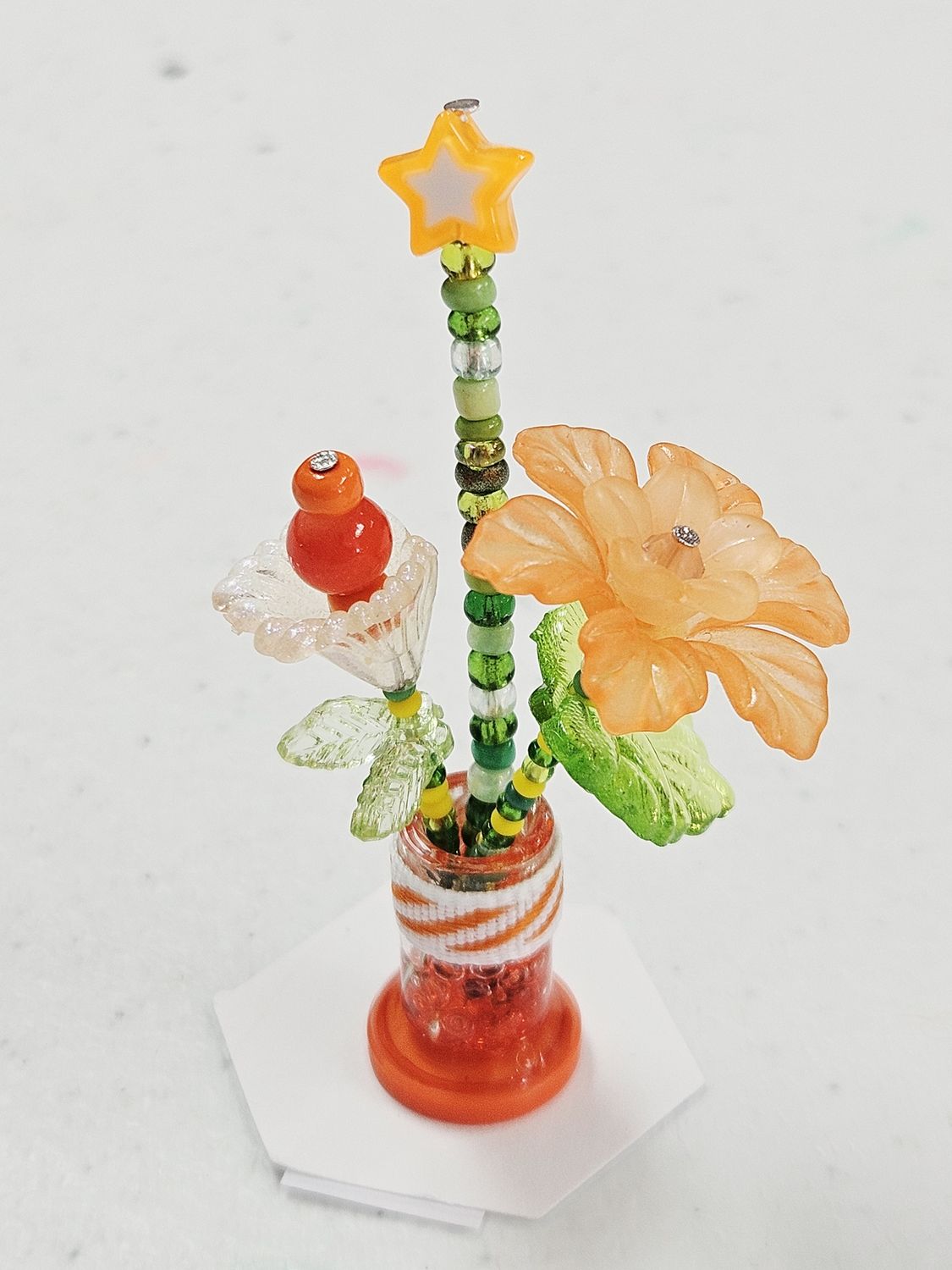 3 orange beaded flowers in glass vase