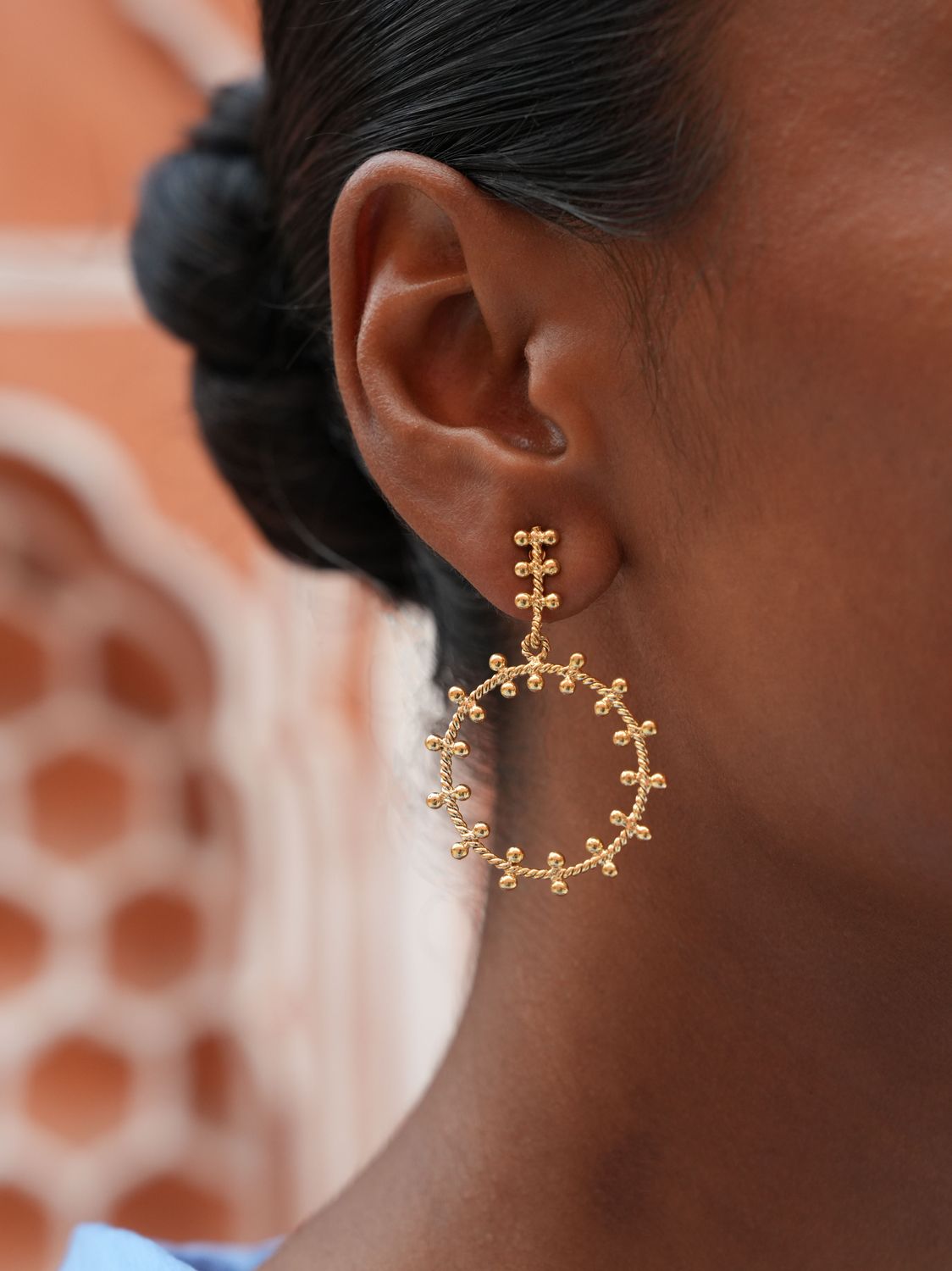 model wearing christine bekaert jewelry handcrafted gold-plated Akkad hoops small earrings 
