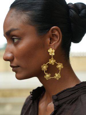 model wearing Christine Bekaert statement jewelry handcrafted gold-plated hand hammered eternelle flower hoops earrings 