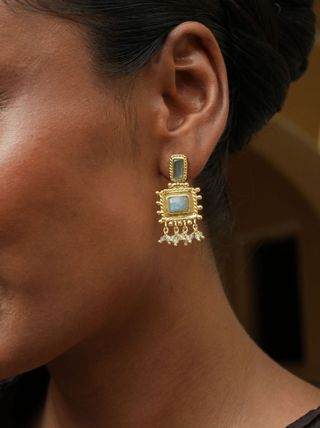 model wearing Christine Bekaert statement jewelry nisaba earrings handcrafted gold-plated with natural gemstones labradorite