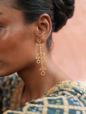 model wearing christine bekaert jewelry handcrafted gold-plated enlil earrings with star design
