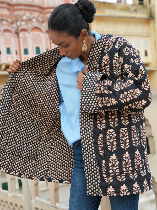 Model wearing a black, short, fully quilted and reversible jacket block printed by hand and designed by Christine Bekaert