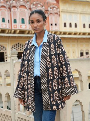 Model wearing a black, short, fully quilted and reversible jacket block printed by hand and designed by Christine Bekaert