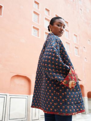 Model wearing short, quilted, fully reversible and handblock printed jacket designed by Christine Bekaert, red and blue 