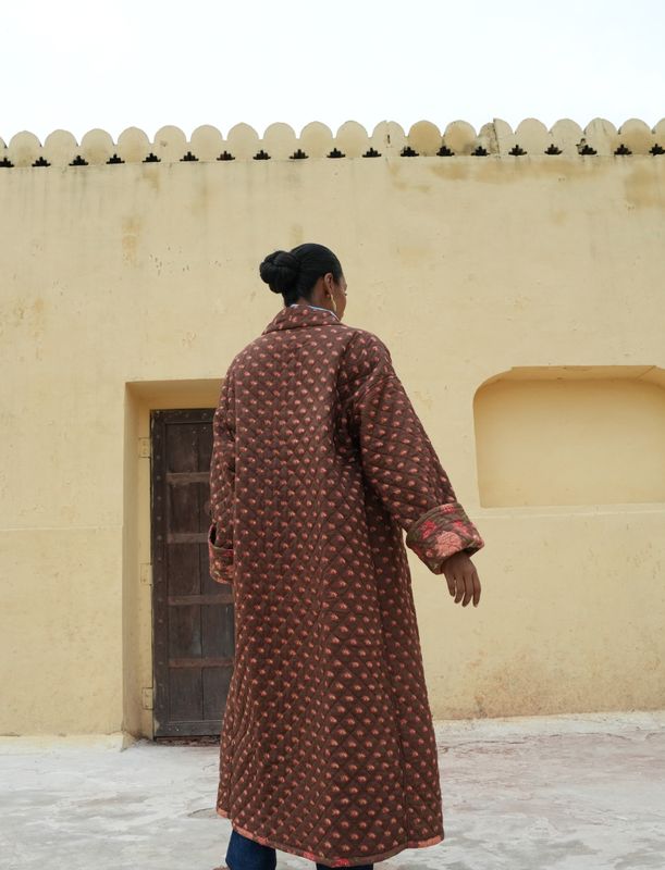 Model wearing long, quilted, fully reversible and handblock printed jacket designed by Christine Bekaert, brown base