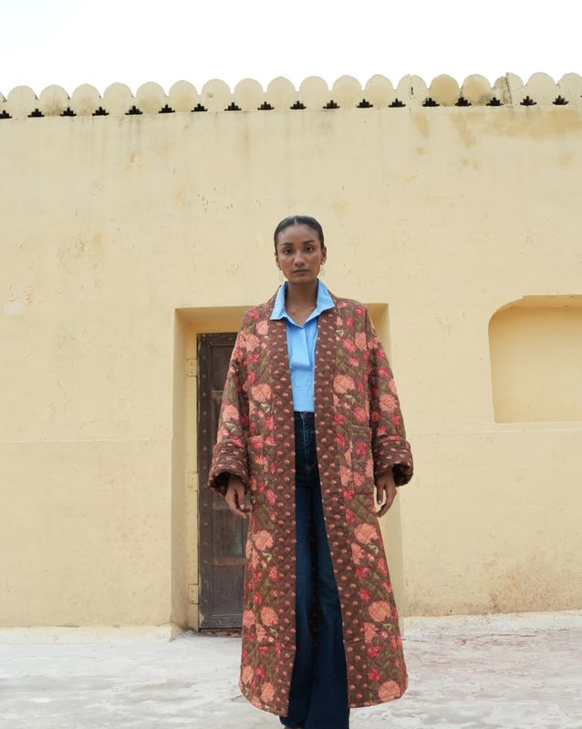 Model wearing long, quilted, fully reversible and handblock printed jacket designed by Christine Bekaert, brown base, front