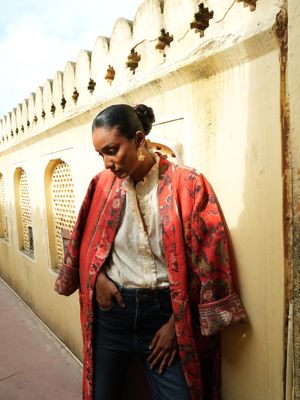 Model wearing long, bright red with flowers jacket designed by Christine Bekaert, a statement piece made from old sarees