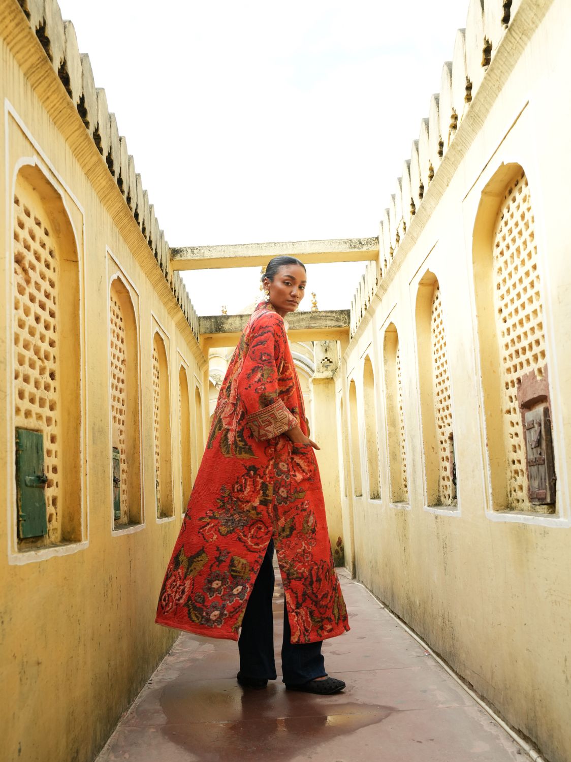 Model wearing long, bright red with flowers jacket designed by Christine Bekaert, a statement piece made from old sarees