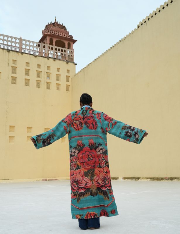 Model wearing long, light blue with red flowers jacket designed by Christine Bekaert, a statement piece made from old sarees