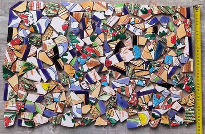 Handbemalte bunte Mosaik-Bruchfliesen mit Maßband zur Größenbestimmung der Stücke
