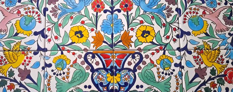Gros plan sur les oiseaux colorés et les fleurs peints à la main sur les carreaux italiens vintage, artisanat traditionnel.
