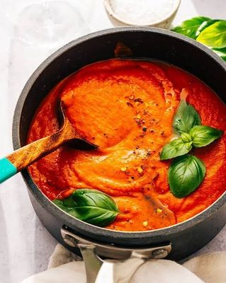 Rich tomato sauce simmering in a pot with fresh basil, representing sauces at Urban Market 1919.