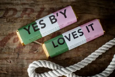 Colourful artisan chocolate bars with playful packaging displayed on a rustic wooden surface.