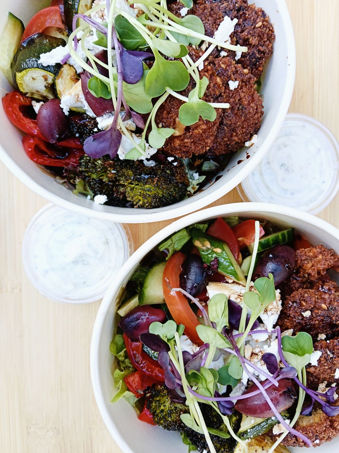 FALAFEL BOWL with seasonal roasted vegetables, greek salad, greens, feta, chickpea and polenta falafel, muhammara, herbed yoghurt sauce and reduced balsamic.