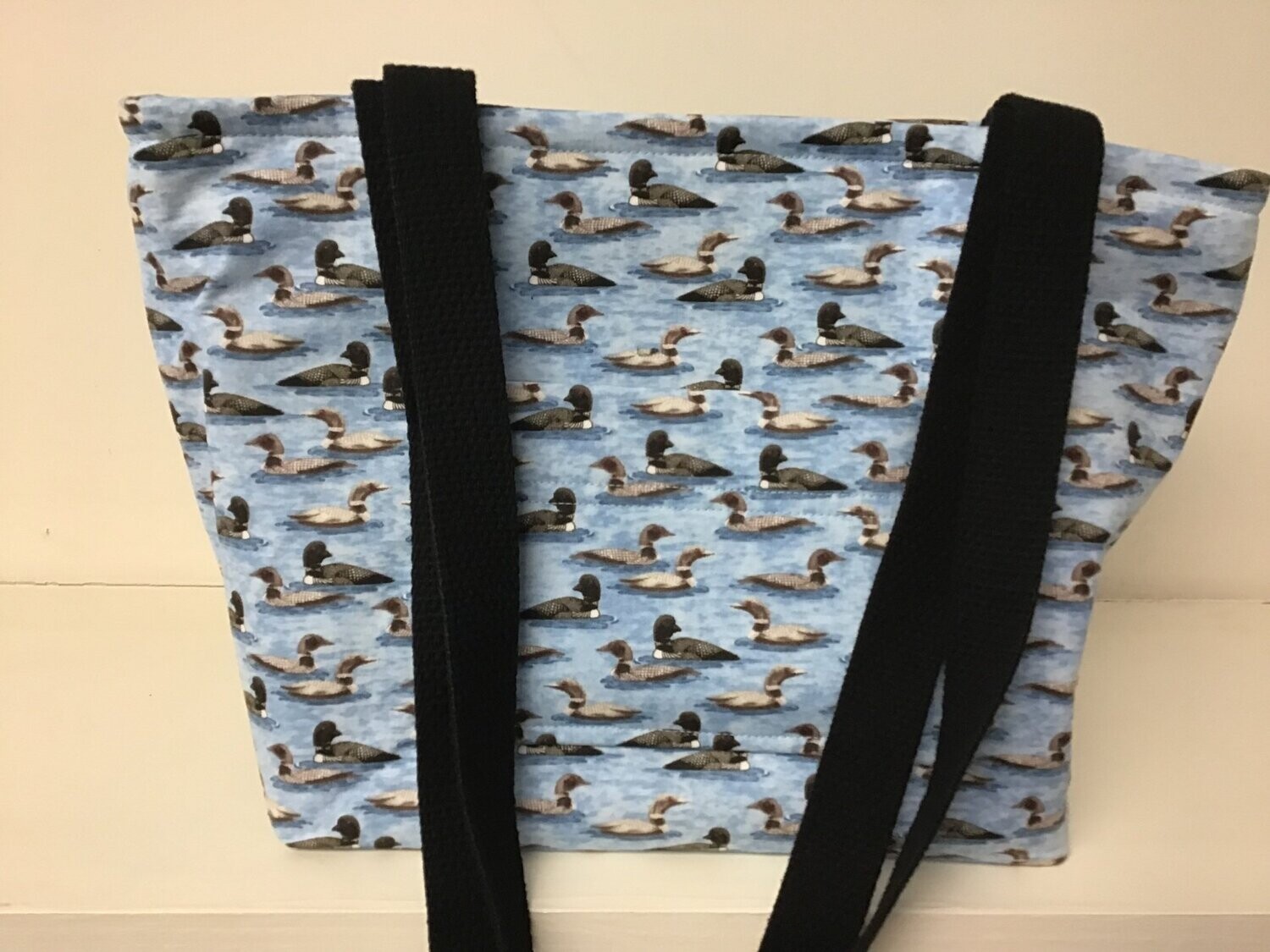 Small loons on blue water, black straps