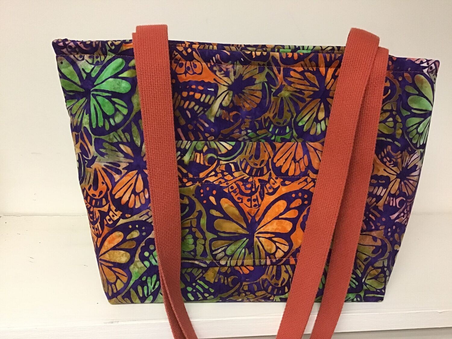 Butterfly batik print in orange, greens, and purple, burnt orange straps