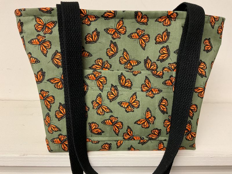 Monarch butterflies on soft green, black straps