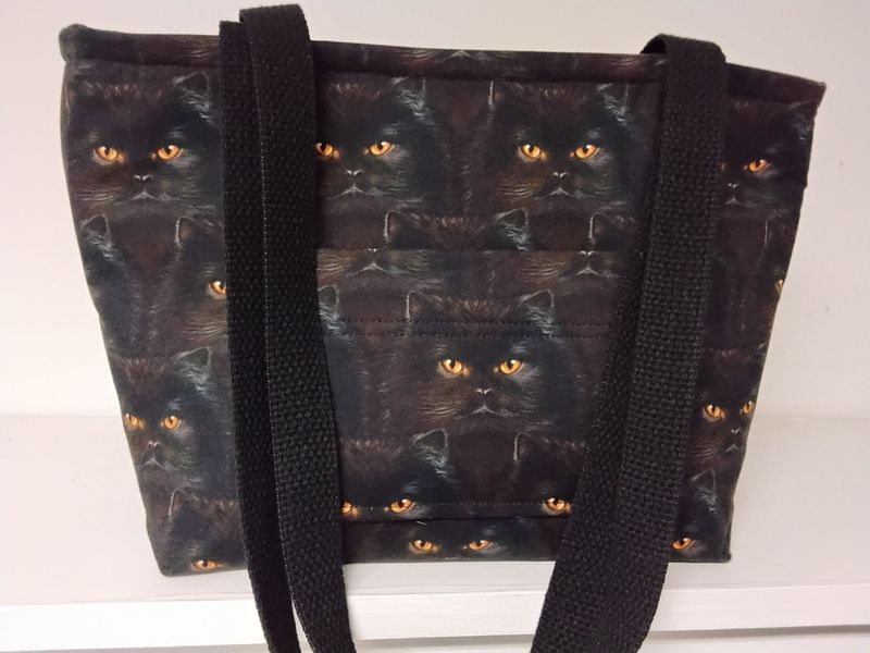 Black cat faces with amber eyes, black straps
