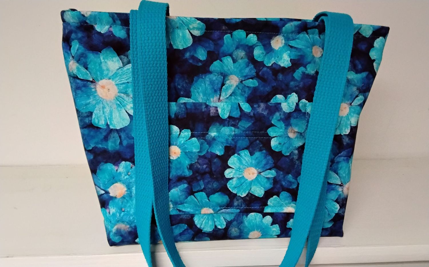 Bright turquoise floral on a dark blue background, turquoise straps