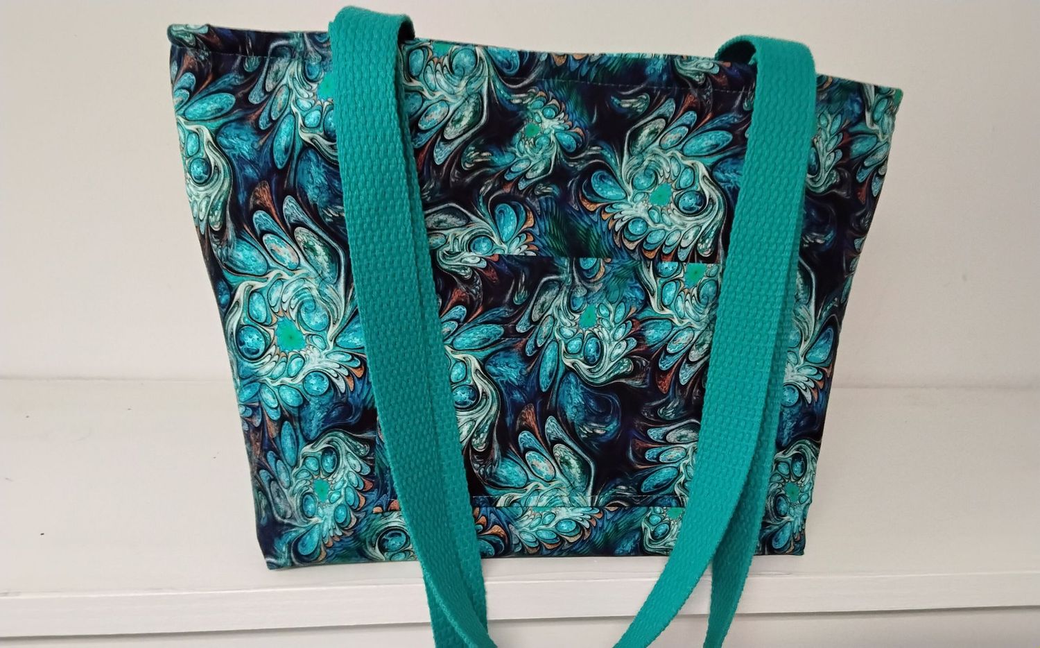 Teal green geometric design on black, teal straps