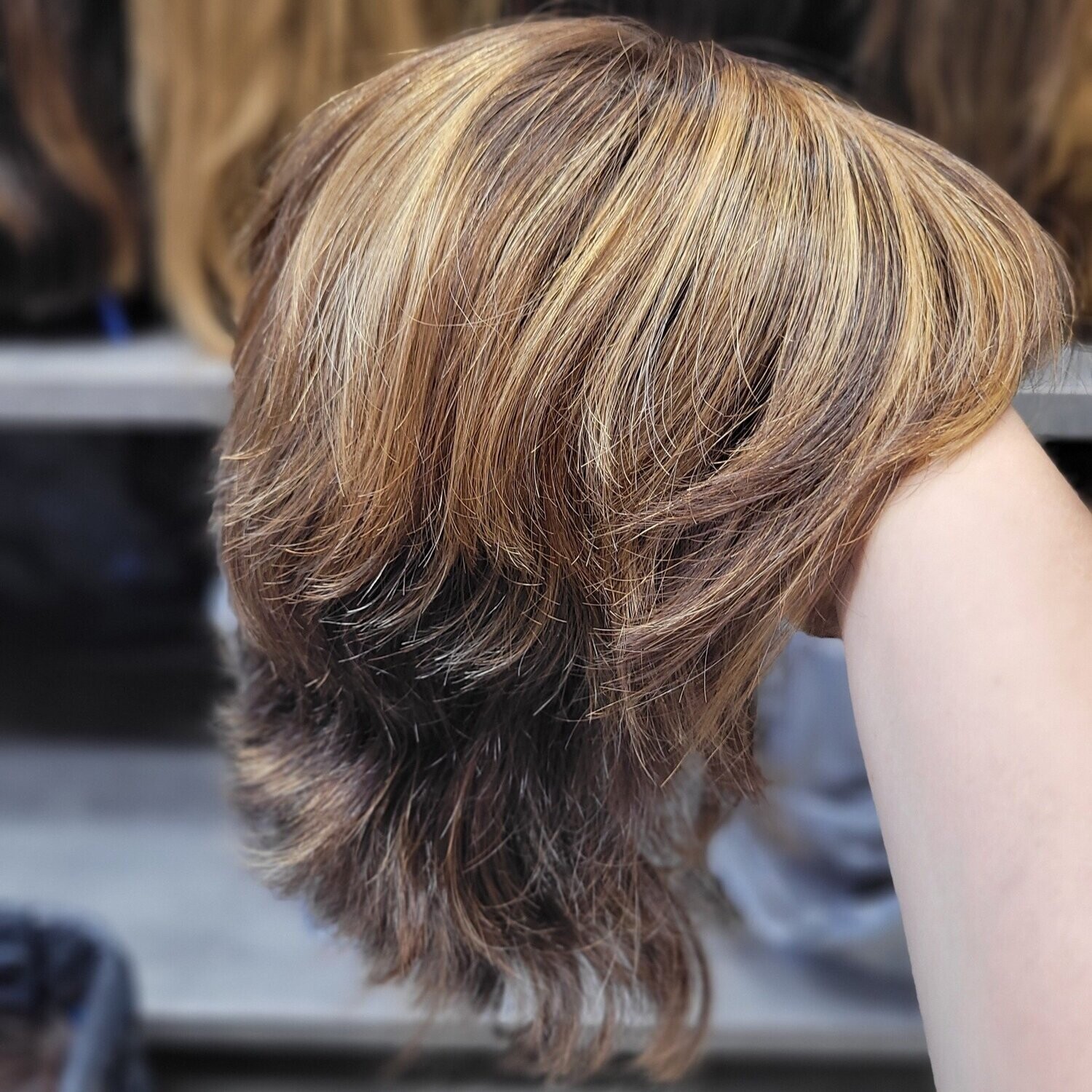 Perruque blonde courte et dégradée tenue sur un bras – #1992