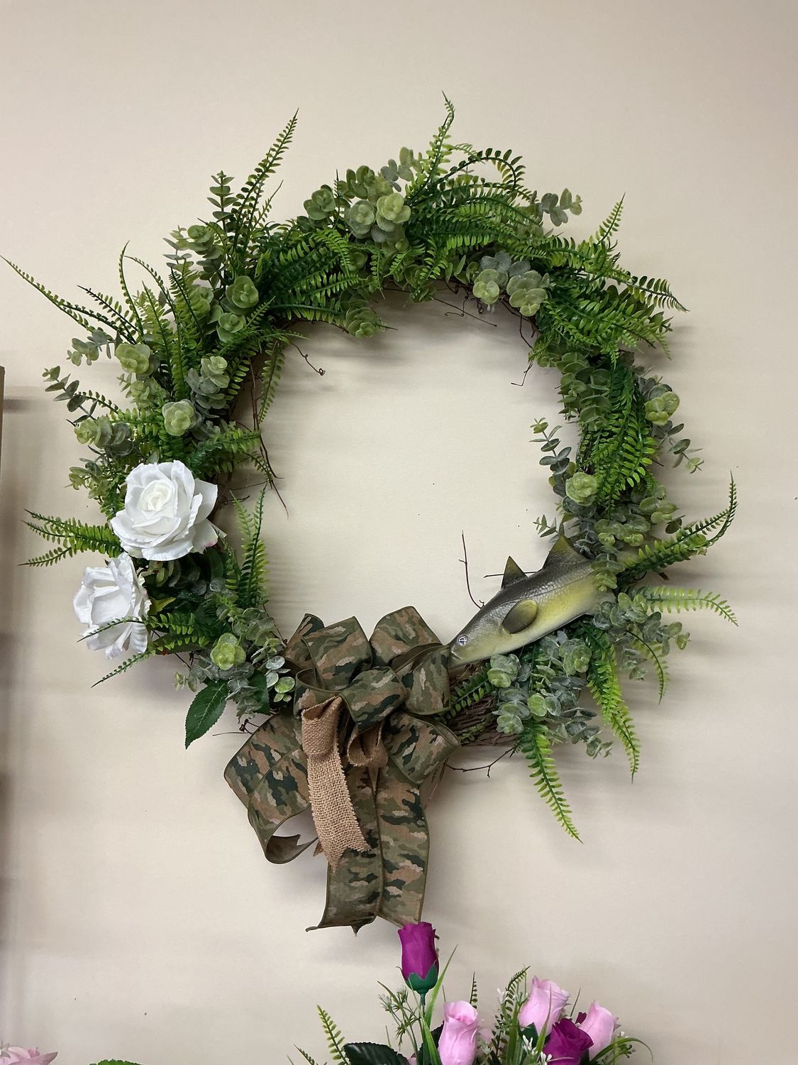 white roses, greenery, fish with hunting bow grapevine wreath