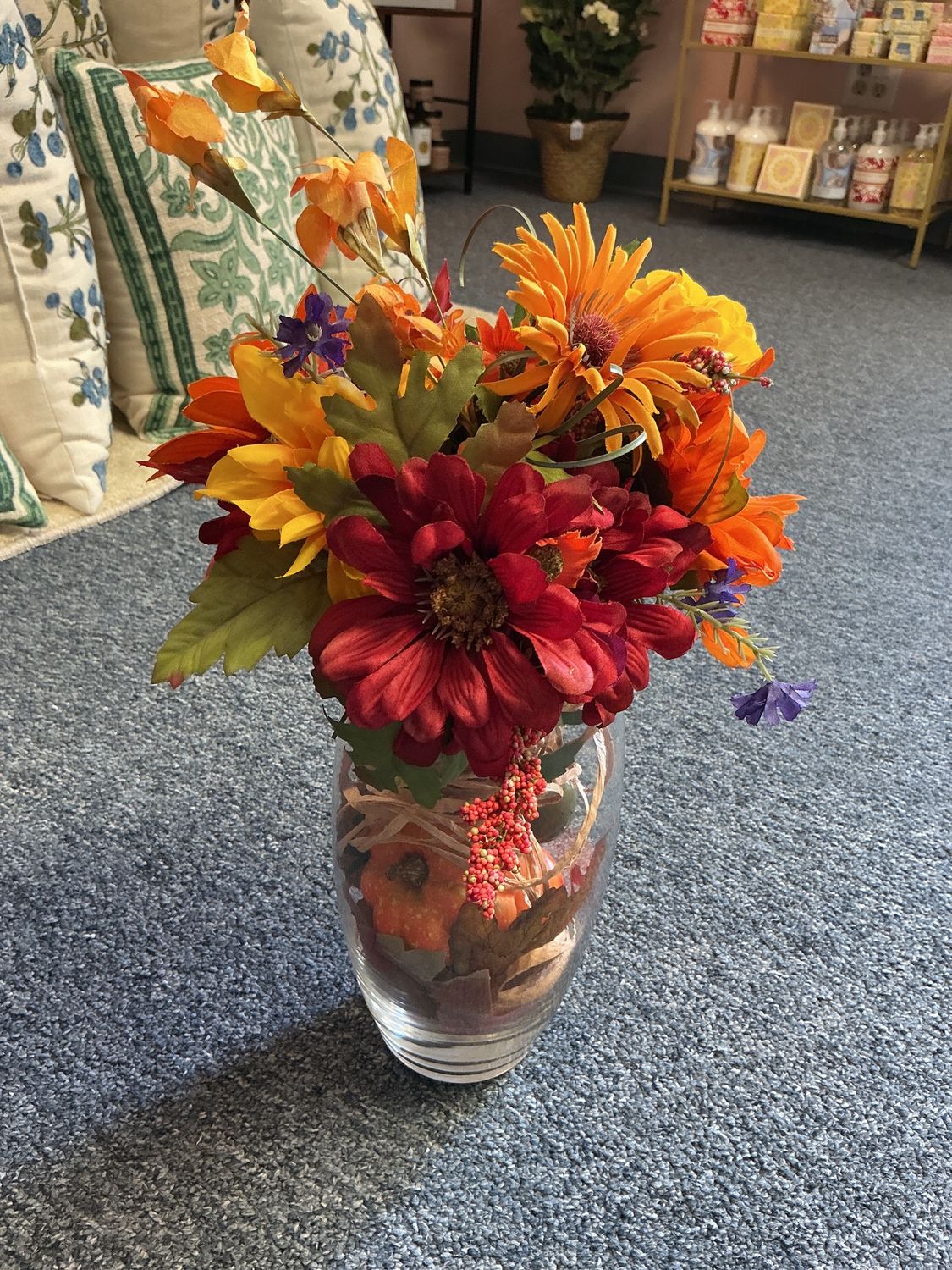 Glass vase with pumpkins and fall flowers