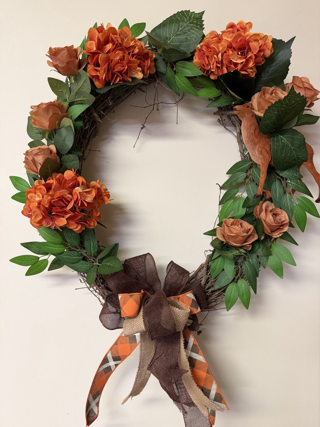 orange hydrangeas and roses with greenery on grapevine wreath with deer