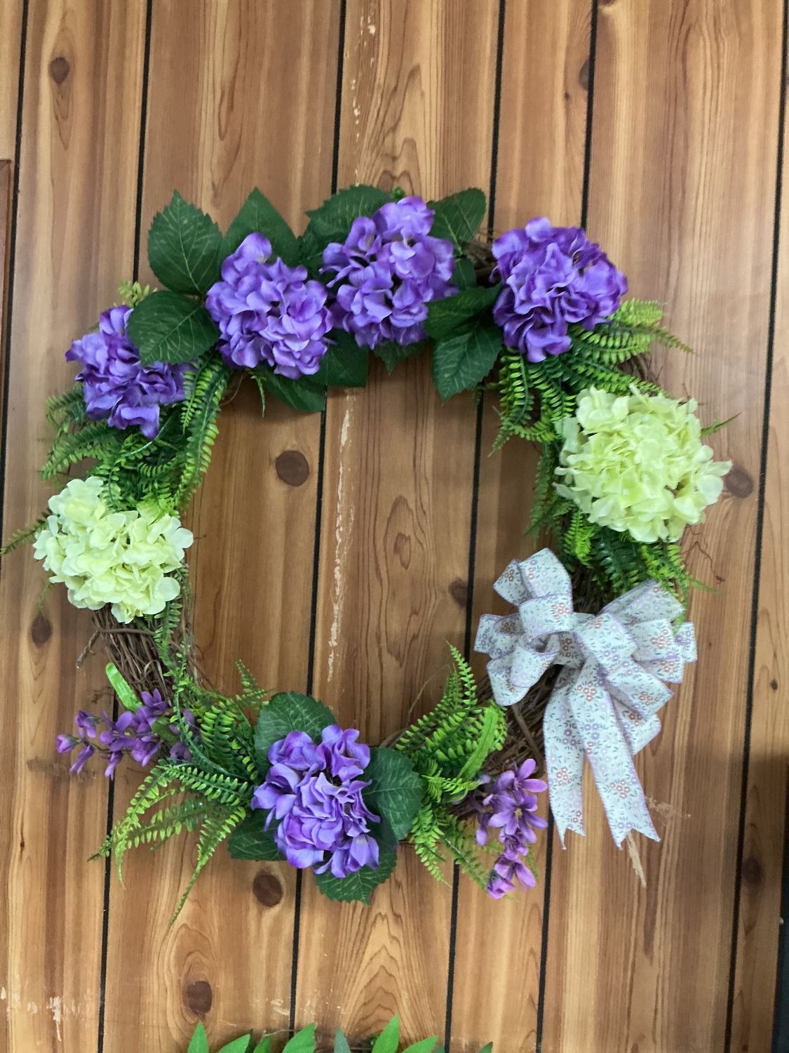 purple and green hydrangeas with greenery grapevine wreath with bow