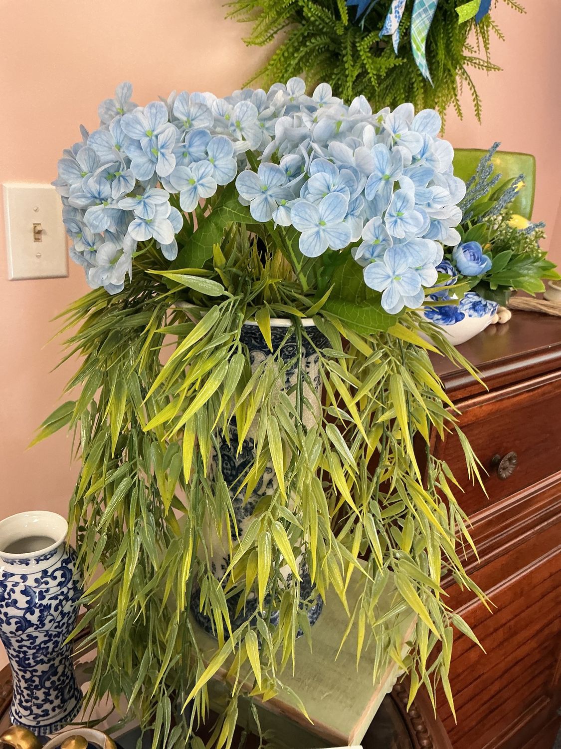 tall blue vase with greenery and blue hydrangeas