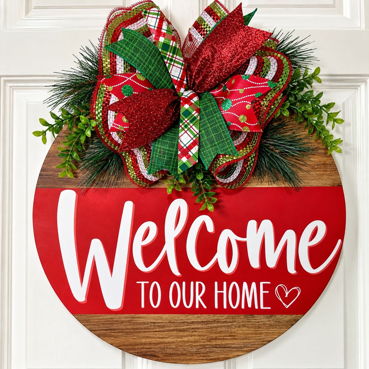 Handmade 18-inch Christmas Welcome to Our Home door hanger with red and green plaid bow, glitter ribbon, evergreen sprigs, an