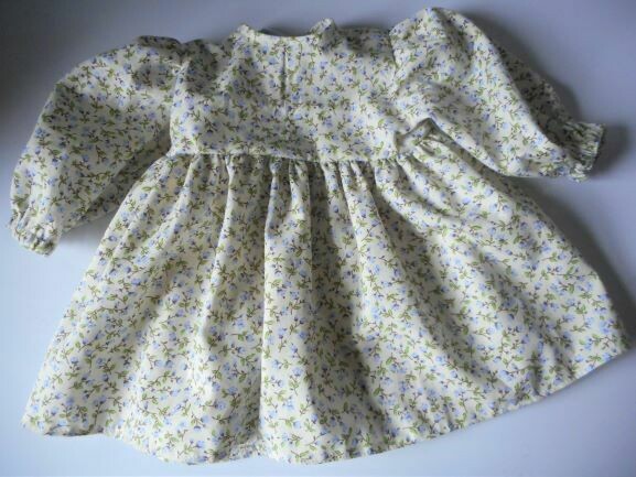 Dress for dolls in a lilac flower print on cream background. Dress for dolls in a lilac flower print on cream background.