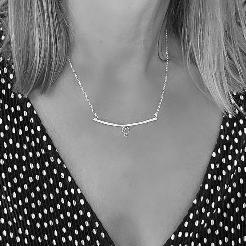 Silver necklace with a curved shape and circles. Handmade in the Harry TiLLEY studio.