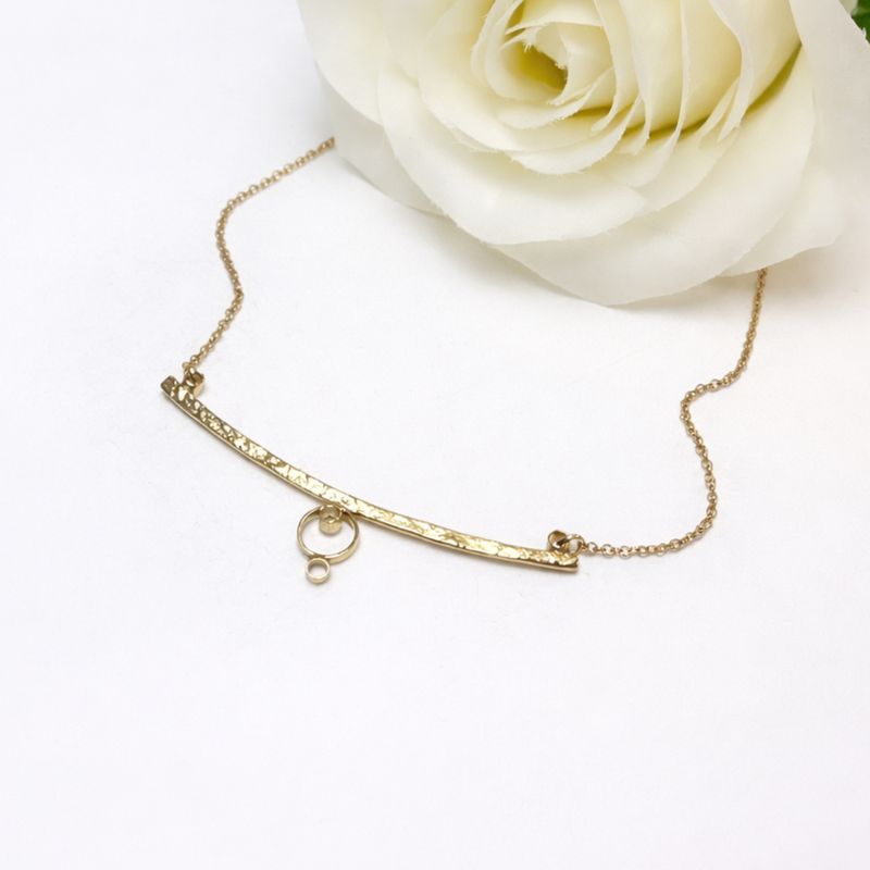 Silver necklace with a curved shape and circles. Handmade in the Harry TiLLEY studio.